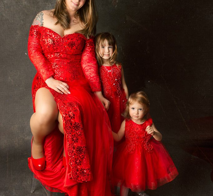 Family portrait. Girls with mother in beautiful red gowns