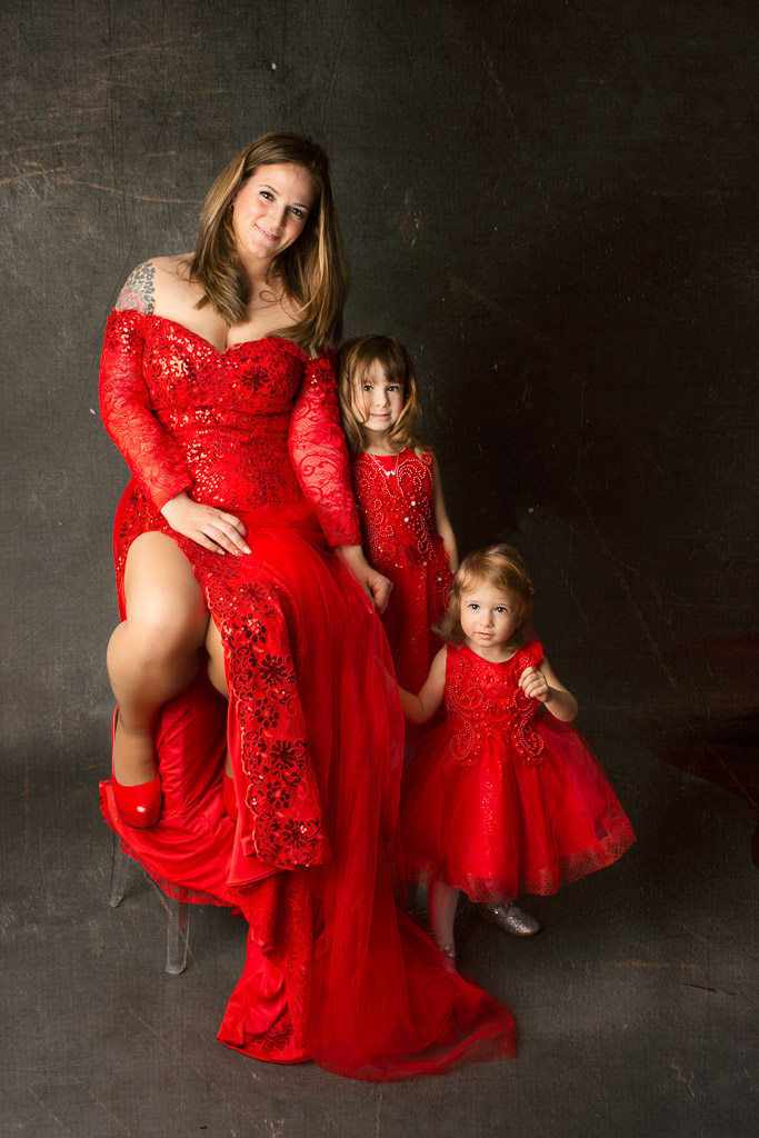 Family portrait. Girls with mother in beautiful red gowns