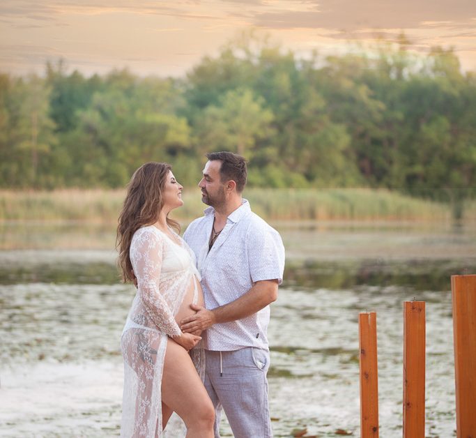 Gorgeous couple poses near lake during maternity session