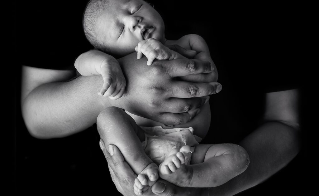 black and white image of baby in father's hands