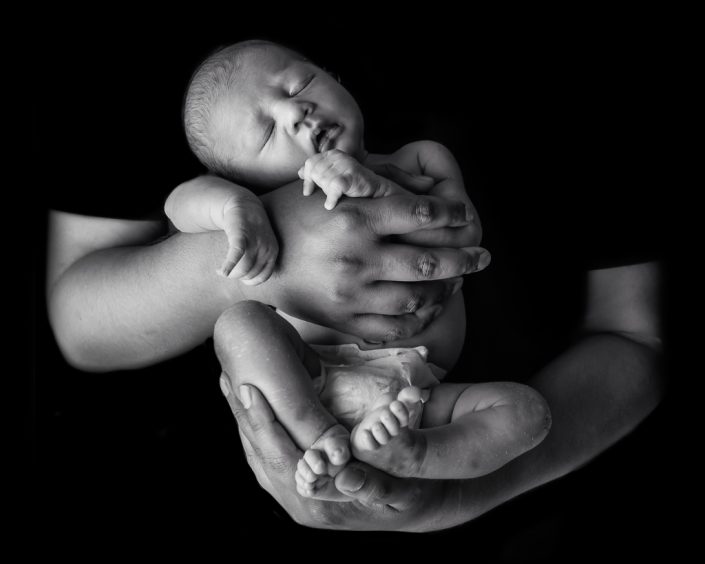 black and white image of baby in father's hands