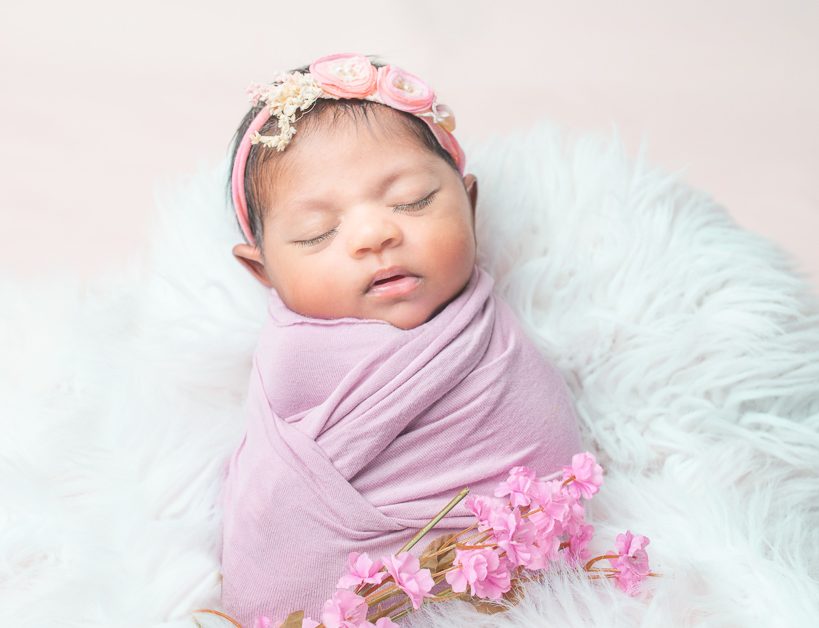 Stunningly Beautiful Newborn baby girl in a pink wrap with flowers