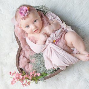 Beautiful baby girl in pink tulle gown in a heart bowl