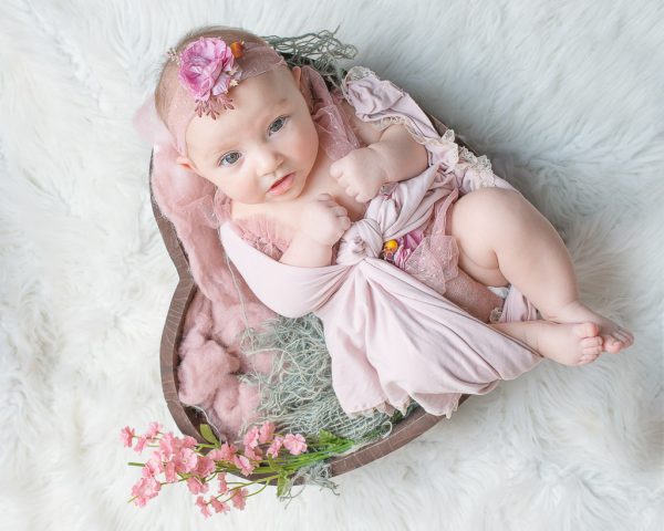 Beautiful baby girl in pink tulle gown in a heart bowl