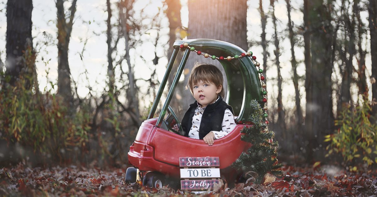 Little Boy poses in Little car during Family Photo Session
