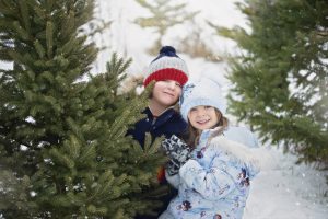 Two children pose for a photo on a Christmas Tree Farm